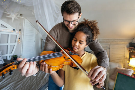 Music is so much fun. Young father teaching his little daughter to play violin and smiling.の写真素材