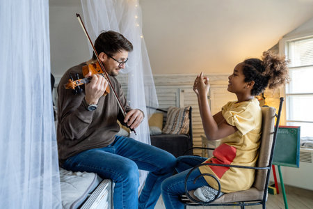 Young man musician teaching a teen girl to play violin. Education music instrument happiness conceptの写真素材