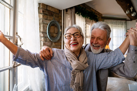 Happy mature woman dancing with her senior husband at home, active healthy senior coupleの写真素材