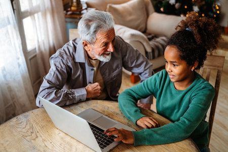 Mature couple with grandchild look at laptop screen and learn how to make video call or use laptopの写真素材