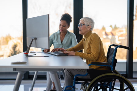 The image includes a person using a wheelchair, depicting inclusivity and teamwork in modern officeの写真素材