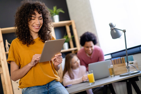 Happy multiethnic teenagers holding technology gadgets using digital devices studying together.の写真素材