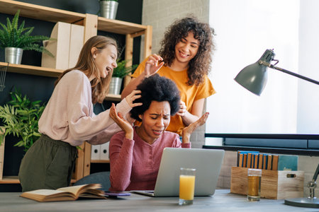 Black mother using computer and trying to focus on work while her teenager children disturb herの写真素材