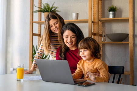 Woman enjoying digital devices with her children and spending funny moments together at home.の写真素材