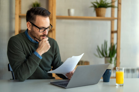 Business man accountant analyst holding documents, work at laptop computer doing online trade marketの写真素材