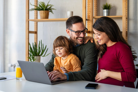 Parents and child relaxing at home with computer watching funny internet video, making online callの写真素材