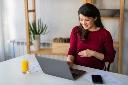 Pregnant woman having an online conference video call with her colleagues while working from home.の写真素材
