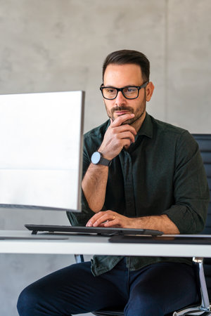 Young happy successful business man working with computer in corporate officeの写真素材