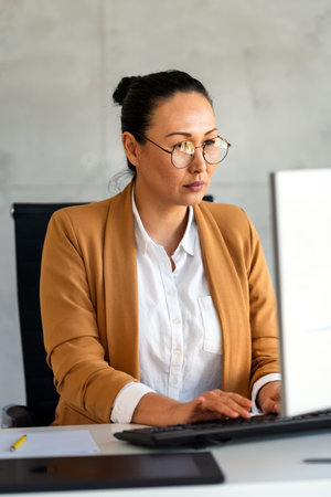 Young happy successful business woman working with computer in corporate officeの写真素材