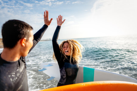 Young beautiful couple of friends on the sea with surfboards in their hands, sports active lifestyleの写真素材