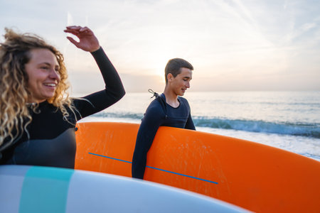Young beautiful couple of friends on the sea with surfboards in their hands, sports active lifestyleの写真素材
