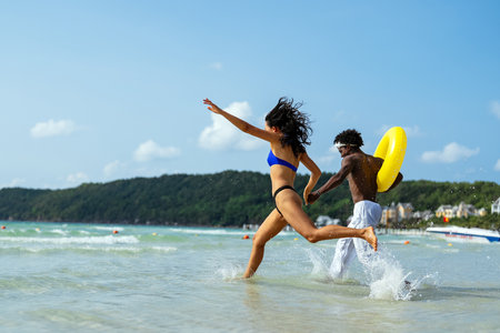 Interracial couple enjoying a romantic beach getaway, embracing love, laughter, and togethernessの写真素材