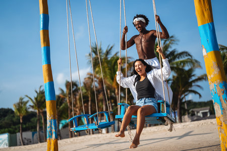 Interracial couple enjoying the freedom of summer, laughing and playing on a tropical beachの写真素材