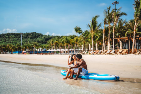Interracial couple celebrating love on a tropical beach, embracing diversity, romance, togethernessの写真素材