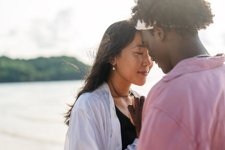 Interracial couple enjoying a romantic beach getaway, embracing love, laughter, and togethernessの写真素材