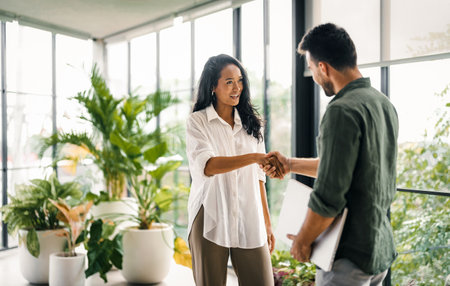 Two happy diverse multiethnic people working, talking in corporate officeの写真素材
