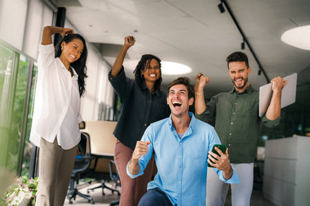 Overjoyed young multiethnic colleagues celebrating shared corporate success or goal achievementの写真素材
