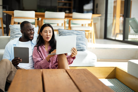 Happy multiethnic diverse couple, people using digital laptop for online shopping or payment.の写真素材