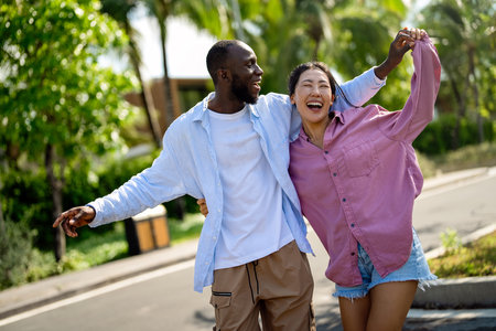 Happy interracial couple laughing together outdoors, enjoying a carefree moment of love, joyの写真素材
