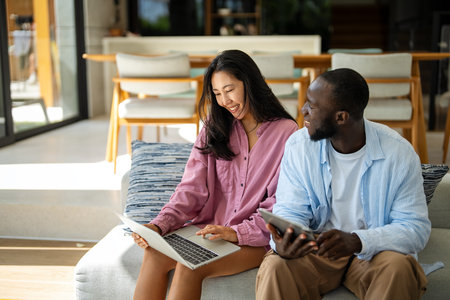 Multiethnic freelancer couple enjoy the environment of tropical climate, working on laptop togetherの写真素材