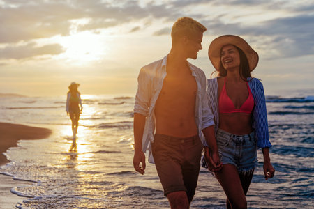 Young beautiful couple walks along the seashore at sunset. Honeymoon. Romantic trip.の写真素材
