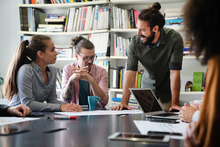 Diverse group of happy employees analyzing reports with digital device, working together in officeの写真素材
