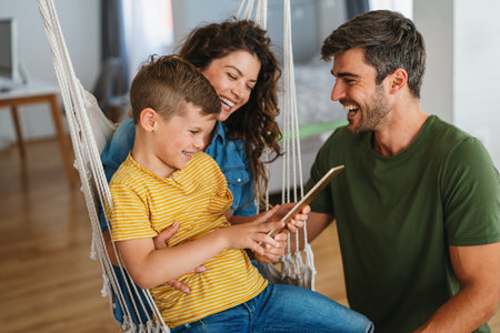 Parents with kid having fun online with application watching video cartoon or playing game on tabletの写真素材