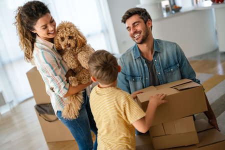 Smiling man and woman enjoy unpacking with child moving to own home. Rent, mortgage conceptの写真素材