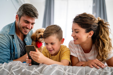 Happy family and kid having fun with smartphone, digital gadget at home. People, technologyの写真素材