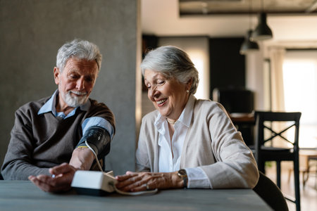 Happy senior couple measuring blood pressure at homeの写真素材