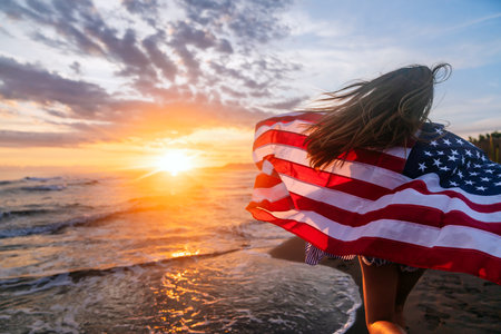 Happy woman running on beach while celebrating independence day and enjoying freedom in USAの写真素材