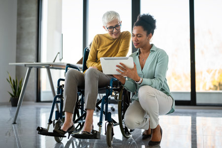 The image includes a person using a wheelchair, depicting inclusivity and teamwork in modern officeの写真素材