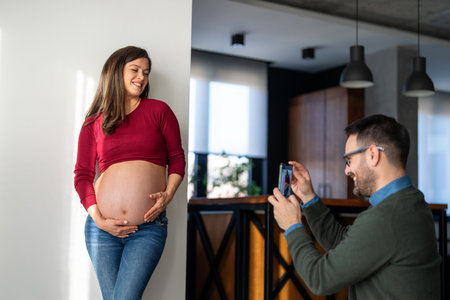 Pregnant woman with her husband taking photos. Happy couple who cant wait to become parentsの写真素材