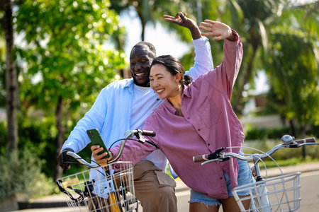 Interracial couple enjoying a joyful bike ride, celebrating love, diversity, and togethernessの写真素材