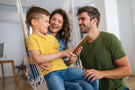 Parents and child relaxing at home with computer watching funny internet video, making online callの写真素材