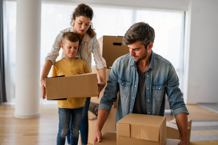Smiling man and woman enjoy unpacking with child moving to own home. Rent, mortgage conceptの写真素材