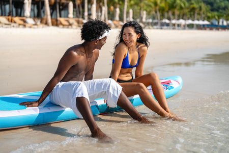 Interracial couple enjoying a romantic beach getaway, embracing love, laughter, and togethernessの写真素材