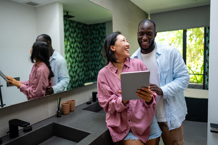 Overjoyed multiethnic couple using laptop, shopping online, playing game togetherの写真素材