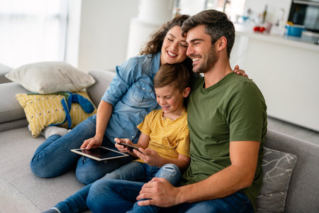 Happy family and kid having fun with smartphone, digital gadget at home. People, technology