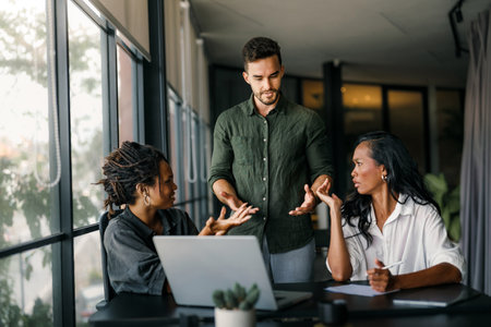A manager frustrated addresses two employees during a work discussion in a modern officeの写真素材