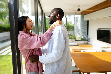 Young diverse multiethnic couple moving in new home. Couple is having fun in new house at moving dayの写真素材