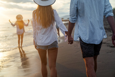 Young happy interracial couple walking on beach smiling, enjoying summer vacation, honeymoonの写真素材