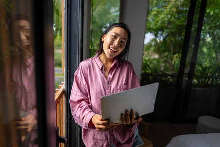 Middle eastern, asian woman managing her online banking, social life, and tasks on a laptopの写真素材