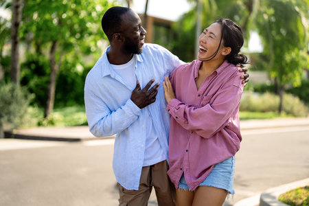 Happy interracial couple laughing together outdoors, enjoying a carefree moment of love, joyの写真素材