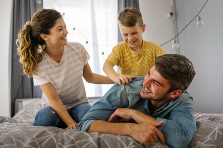 Happy family leisure. Cheerful mother, father and son having fun together on weekend at homeの写真素材