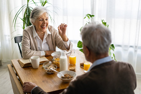 Beautiful senior couple having fun, smiling together while enjoying breakfast togetherの写真素材