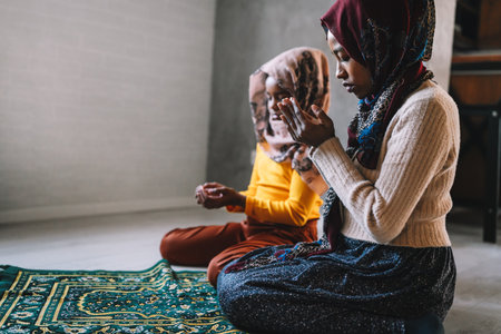 Beautiful muslim mother and child performing islamic prayersの写真素材