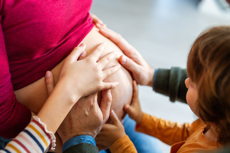 Lovely children touching mothers pregnant belly. Happy little siblings feeling baby at mother tummyの写真素材