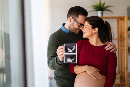Woman and her boyfriend holding up an image of her sonogram of the baby. New family, love, baby