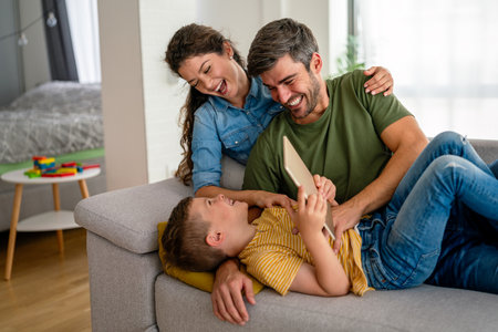 Parents with kid having fun online with application watching video cartoon or playing game on tablet